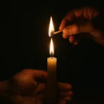 Mãos acendendo uma vela em meio à escuridão, simbolizando o despertar da luz interior e o caminho espiritual de autotransformação — imagem para curiosavida.com.br.